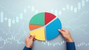 雙手正在拼湊調整圓餅圖模型的不同色塊，背景為淡藍色調的金融股票K線走勢圖，隱喻在通膨與市場波動中，進行理性且動態的資產配置防禦策略。